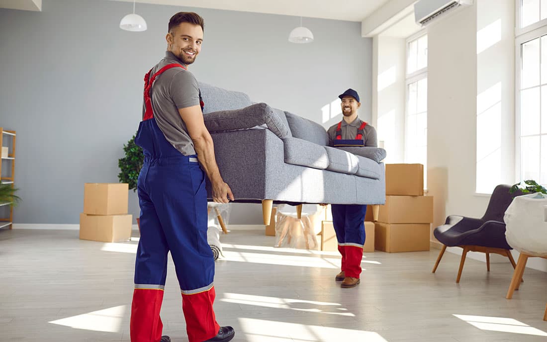 Mitarbeiter eines Umzugsunternehmens tragen ein Sofa - Querformat